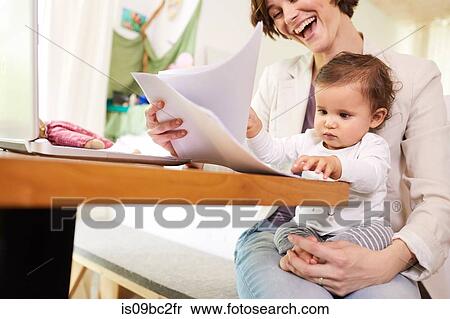 Mother looking at paperwork with baby girl sitting on her lap View Large Photo Image Stock Photography - Mother looking at paperwork with baby girl sitting on her lap. Fotosearch