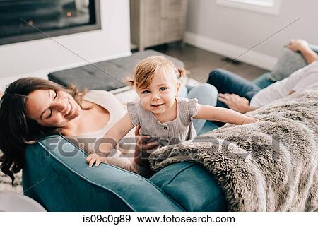 Stock Photo - Mother playing with baby daughter on sofa, portrait. Fotosearch