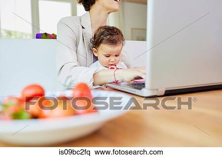 Mother using laptop with baby girl sitting on her lap View Large Photo Image Stock Photography - Mother using laptop with baby girl sitting on her lap. Fotosearch