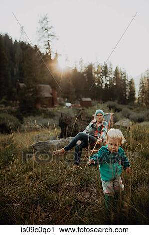 Stock Image - Mother watching toddler daughter playing in rural valley, Mineral King, California, USA. Fotosearch