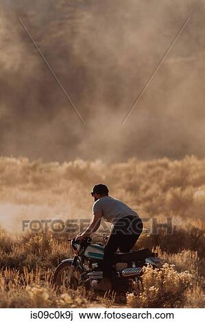 Stock Image - Motorbiker raising dust, Kennedy Meadows, California, US. Fotosearch