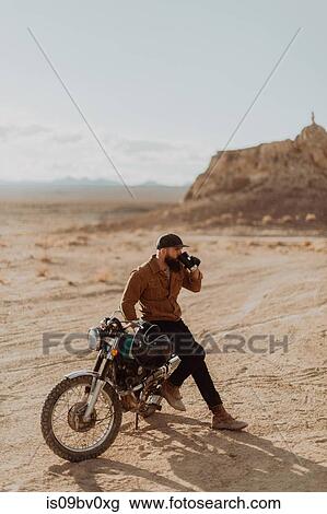 Motorcyclist enjoying drink on stationary bike, Trona Pinnacles, California, US View Large Photo Image Stock Image - Motorcyclist enjoying drink on stationary bike, Trona Pinnacles, California, US. Fotosearch