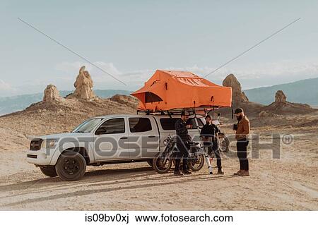 Stock Image - Motorcyclist friends taking break beside off road vehicle, Trona Pinnacles, California, US. Fotosearch