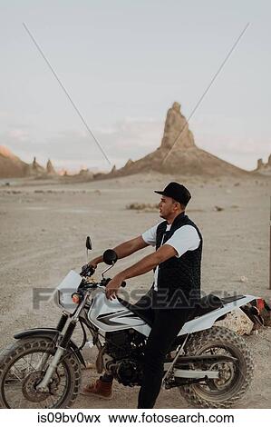 Stock Photo - Motorcyclist on stationary bike, Trona Pinnacles, California, US. Fotosearch