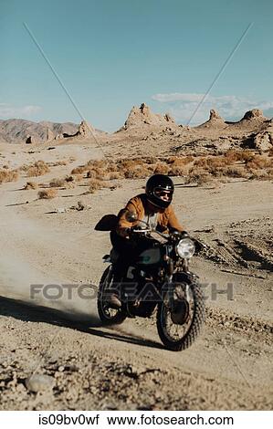Stock Image - Motorcyclist riding in desert, Trona Pinnacles, California, US. Fotosearch