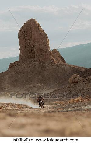 Stock Image - Motorcyclist riding in desert, Trona Pinnacles, California, US. Fotosearch