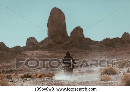 Stock Photo - Motorcyclist riding in desert, Trona Pinnacles, California, US. Fotosearch