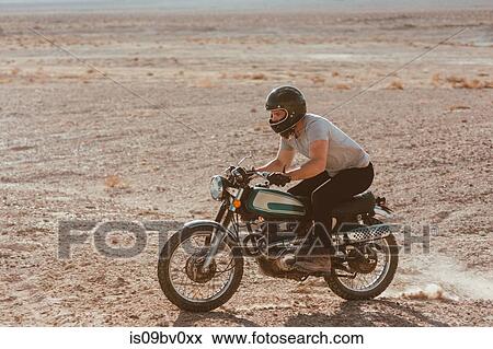 Stock Photo - Motorcyclist riding in desert, Trona Pinnacles, California, US. Fotosearch