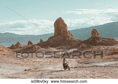 Stock Photo - Motorcyclist riding in desert, Trona Pinnacles, California, US. Fotosearch