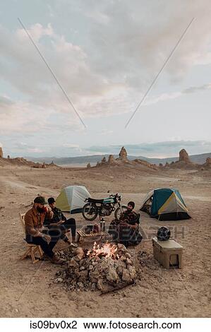 Stock Image - Motorcyclist road trippers around camp fire, Trona Pinnacles, California, US. Fotosearch