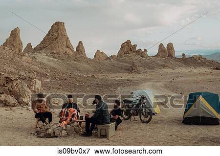 Stock Photo - Motorcyclist road trippers around camp fire, Trona Pinnacles, California, US. Fotosearch