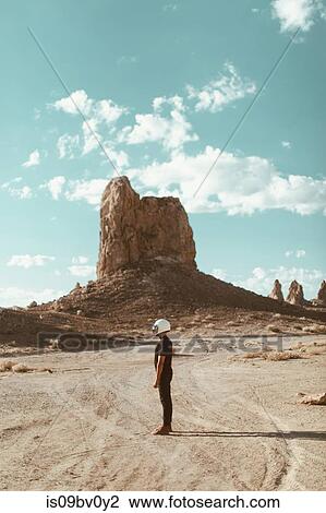 Stock Image - Motorcyclist standing in desert, Trona Pinnacles, California, US. Fotosearch