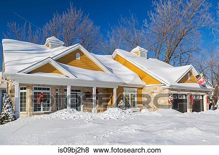 Stock Photo - Natural cut stone with yellow wood cladding country style house facade in winter. Fotosearch
