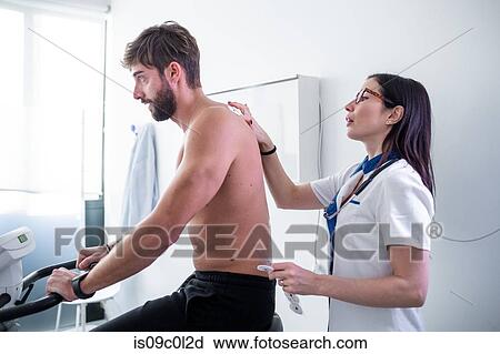 Stock Image - Nurse performing ECG test on patient in consultation room. Fotosearch
