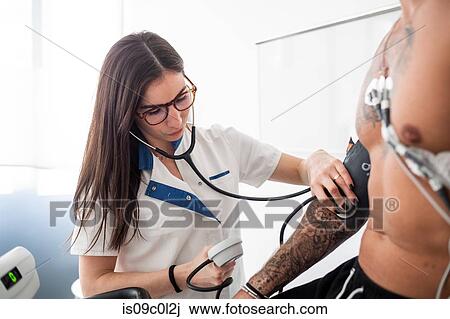 Nurse performing ECG test on patient in consultation room View Large Photo Image Stock Image - Nurse performing ECG test on patient in consultation room. Fotosearch