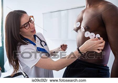 Stock Photography - Nurse performing ECG test on patient in consultation room. Fotosearch