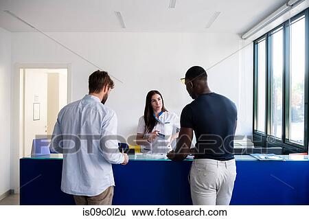 Nurse speaking with patients at hospital reception View Large Photo Image Stock Photograph - Nurse speaking with patients at hospital reception. Fotosearch