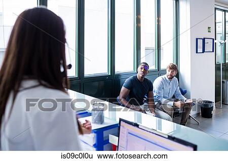 Nurse speaking with patients completing forms at hospital reception View Large Photo Image Stock Photograph - Nurse speaking with patients completing forms at hospital reception. Fotosearch