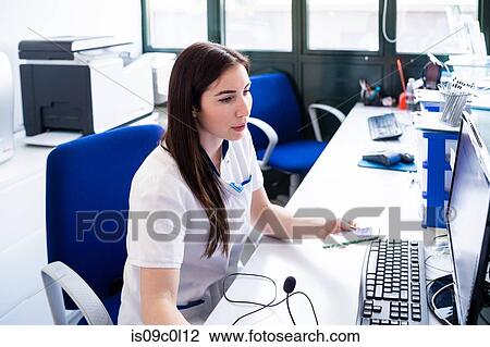 Nurse working on computer at hospital reception View Large Photo Image Stock Image - Nurse working on computer at hospital reception. Fotosearch