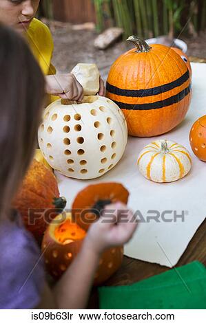 Over shoulder view of girl and brother preparing pumpkins on garden table View Large Photo Image Stock Photography - Over shoulder view of girl and brother preparing pumpkins on garden table. Fotosearch