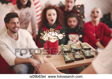 Over shoulder view of young woman serving friends with christmas biscuits at christmas party View Large Photo Image Stock Photograph - Over shoulder view of young woman serving friends with christmas biscuits at christmas party. Fotosearch
