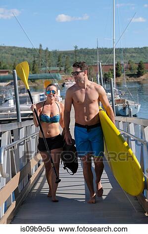 Paddleboarding couple carrying paddleboard on lake pier, Frisco, Colorado, USA View Large Photo Image Stock Photograph - Paddleboarding couple carrying paddleboard on lake pier, Frisco, Colorado, USA. Fotosearch