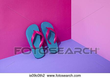 Stock Image - Pair of colourful flip-flops leaning on wall. Fotosearch
