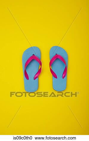 Stock Image - Pair of colourful flip-flops on sandy beach. Fotosearch