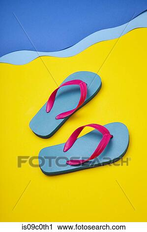 Stock Image - Pair of colourful flip-flops on sandy beach by sea. Fotosearch