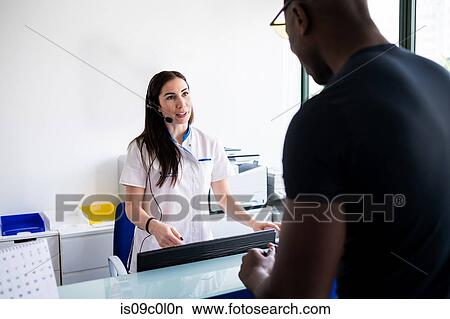 Patient speaking with nurse at hospital reception View Large Photo Image Picture - Patient speaking with nurse at hospital reception. Fotosearch