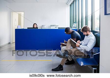 Patients completing forms at hospital reception View Large Photo Image Stock Photograph - Patients completing forms at hospital reception. Fotosearch