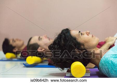 Stock Image - People at yoga class resting head on block. Fotosearch