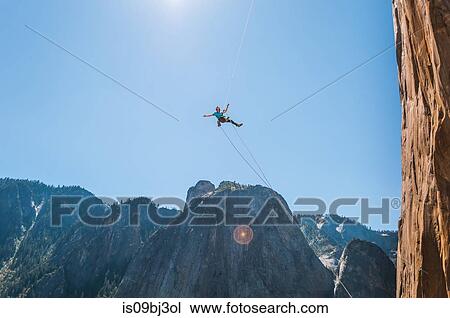 Person swinging mid air against blue sky on alcove swing at the base of El Capitan, Yosemite Valley, California, USA View Large Photo Image Stock Image - Person swinging mid air against blue sky on alcove swing at the base of El Capitan, Yosemite Valley, California, USA. Fotosearch