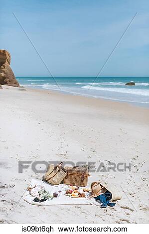 Stock Image - Picnic blanket and basket on empty beach, Menemsha, Martha's Vineyard, Massachusetts, USA. Fotosearch
