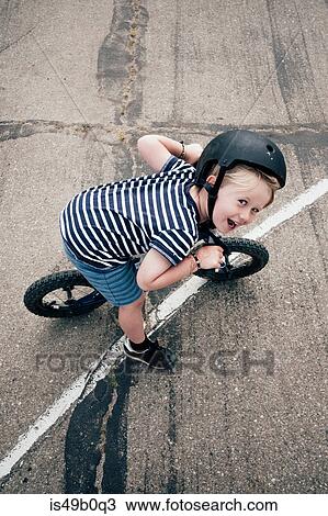 Stock Image - Portrait of boy outdoors, riding bicycle, elevated view. Fotosearch