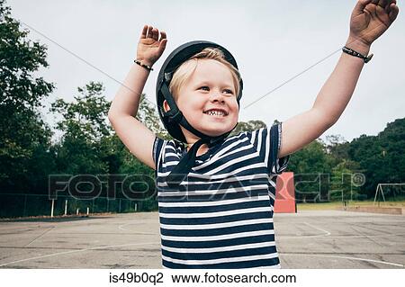 Stock Image - Portrait of boy outdoors, wearing safety helmet, smiling. Fotosearch