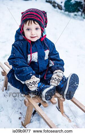 Stock Photo - Portrait of boy wearing ski suit on toboggan. Fotosearch