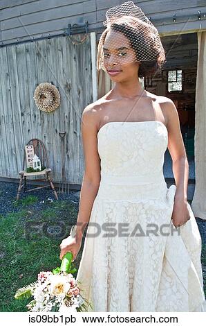 Stock Image - Portrait of bride wearing wedding dress, and veil, outdoors. Fotosearch