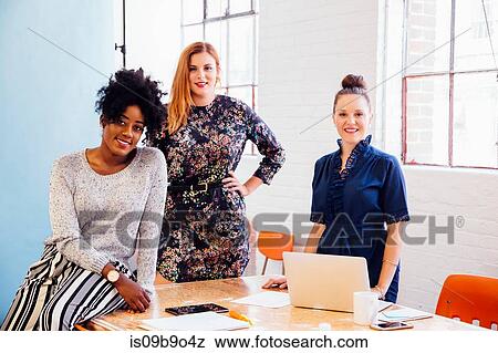 Stock Photo - Portrait of colleagues in office looking at camera smiling. Fotosearch