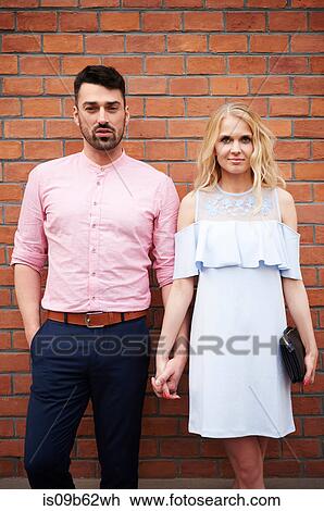 Portrait of couple holding hands in front of brick wall View Large Photo Image Stock Image - Portrait of couple holding hands in front of brick wall. Fotosearch