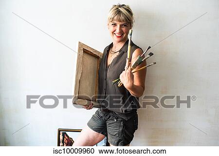 Stock Image - Portrait of fine art painter with painting and paint brushes. Fotosearch
