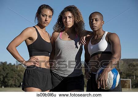 Stock Photograph - Portrait of friends with football looking at camera. Fotosearch