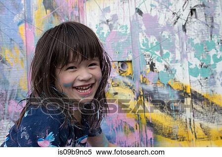 Portrait of girl by painted wall looking at camera smiling View Large Photo Image Stock Photography - Portrait of girl by painted wall looking at camera smiling. Fotosearch