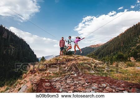 Stock Image - Portrait of man and young women jumping mid air in mountain landscape, Draja, Vaslui, Romania. Fotosearch