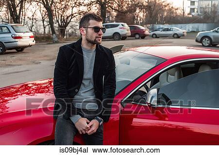 Portrait of man leaning against car looking away View Large Photo Image Stock Image - Portrait of man leaning against car looking away. Fotosearch
