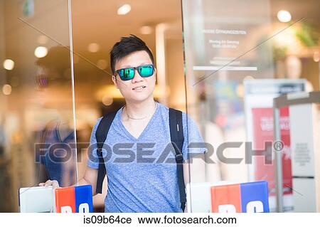 Stock Image - Portrait of man leaving shop wearing sunglasses. Fotosearch