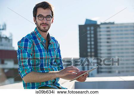 Portrait of man, standing beside office window, using digital tablet View Large Photo Image Stock Image - Portrait of man, standing beside office window, using digital tablet. Fotosearch
