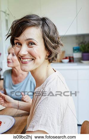 Portrait of mid adult woman at dinner table, smiling View Large Photo Image Stock Image - Portrait of mid adult woman at dinner table, smiling. Fotosearch
