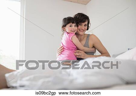 Stock Photography - Portrait of mother and daughter at home, hugging. Fotosearch