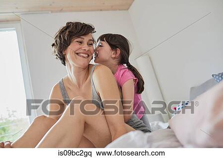 Stock Photography - Portrait of mother and daughter at home, hugging. Fotosearch